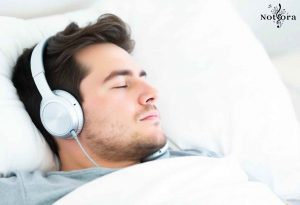 فردی آرام در حال گوش دادن به موسیقی با هدفون در رختخواب و چشمانش را بسته است
